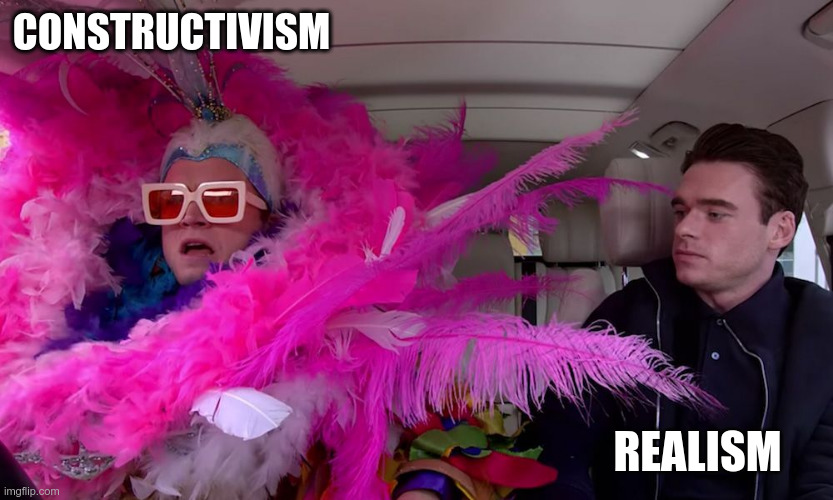 Two people sitting in a car. One has a flamboyant costume, including a huge pink feather boa and thick yellow-rimmed glasses. The other person is dressed plainly in all black and is glaring at the flamoyantly dressed person. The flamboyantly dressed person is labeled 'constructivism' and the plainly dressed person in labeled 'realism'