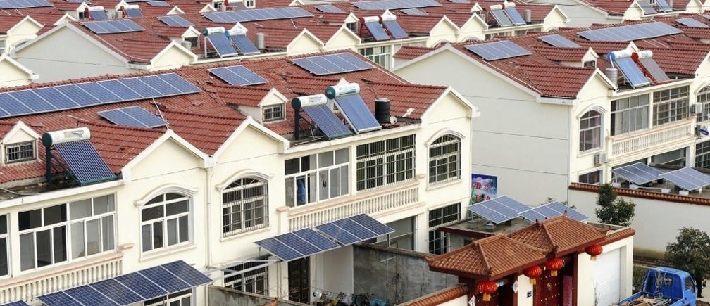 photograph of many houses, all of which have solar panels on top their roofs