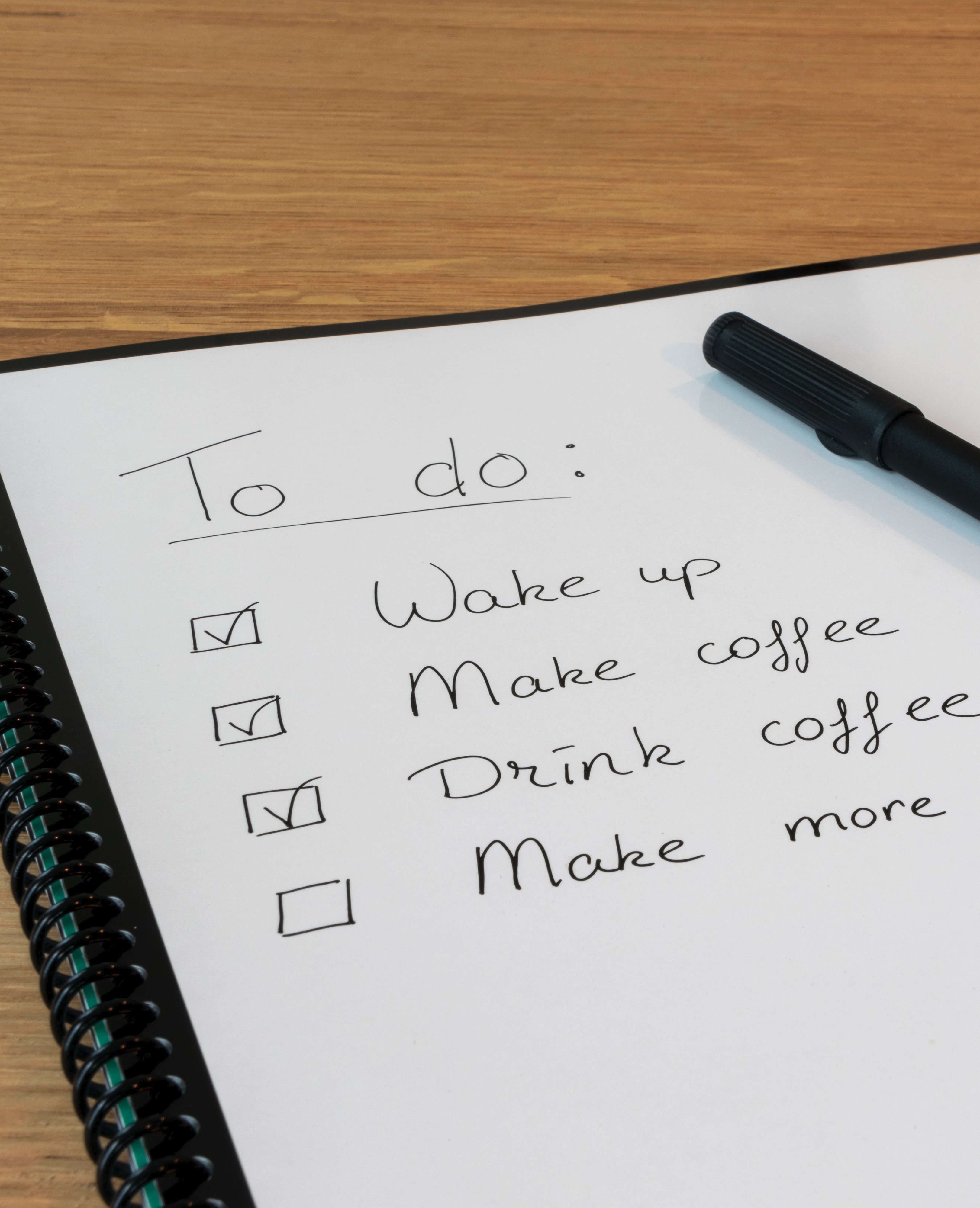 A close-up of a handwritten to-do list that has boxes for 'wake up' 'make coffee' 'drink cofee' and 'make more coffee'
