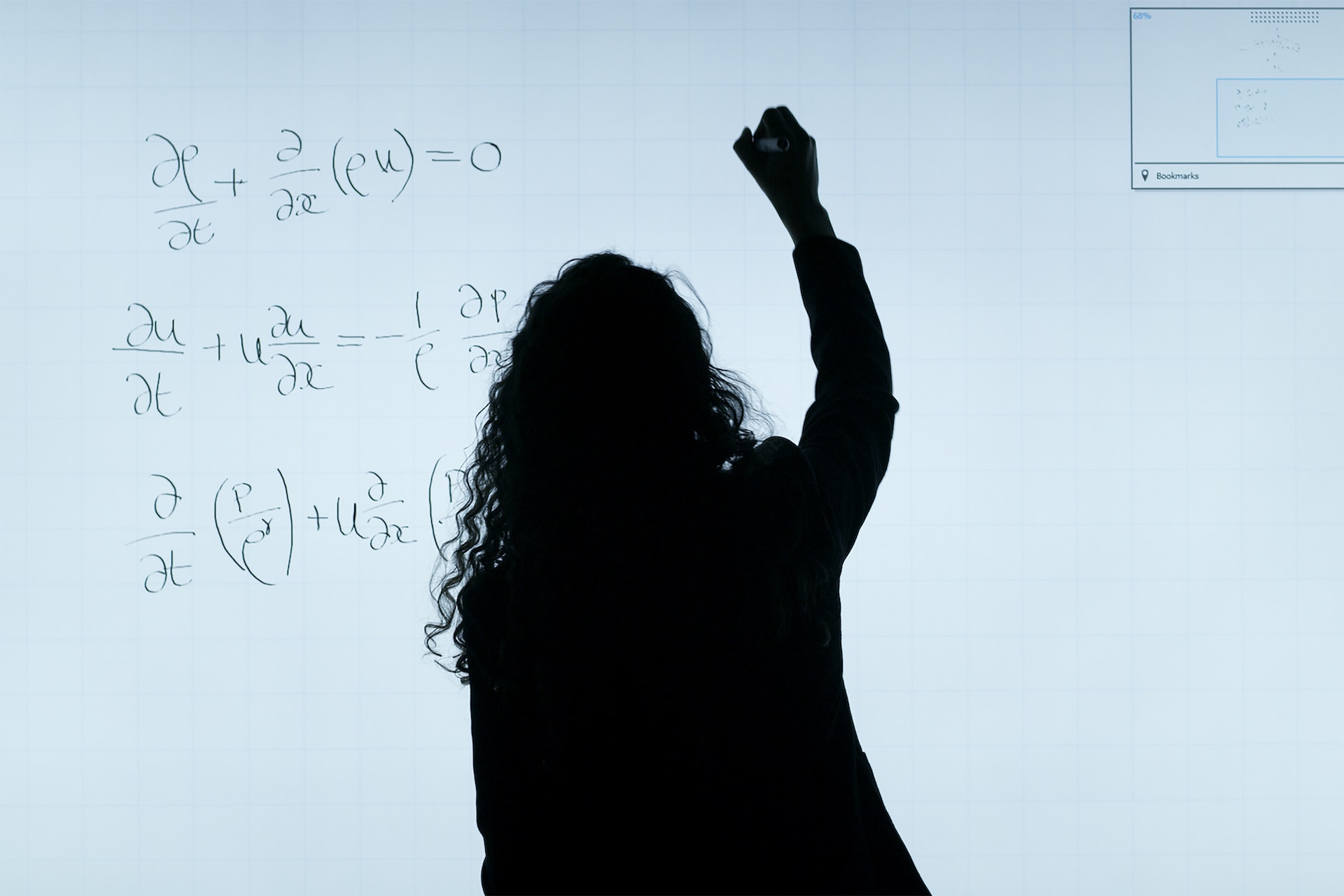 A person siloutted against a whiteboard covered in differential equations